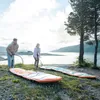Two people are inflating paddleboards by a lake. Náhľad obrázku produktu