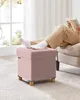 A person is relaxing with their feet up on a pink ottoman in a well-lit room. Náhled obrázku produktu