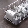 A clear plastic organizer box filled with white and gray charging cables and power adapters, placed on a wooden surface. Produktbild-Vorschau