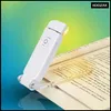 A white LED book light clips onto an open book, illuminating the pages. Náhľad obrázku produktu