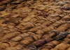 A close-up view of a woven texture, likely made from natural fibers like rattan or banana leaves, in various shades of brown. Produktbild-Vorschau