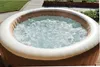 An inflatable hot tub filled with bubbling water sits on a patio next to a lawn. Náhľad obrázku produktu