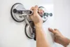 A person is using a triple suction cup lifter to hold a white panel. Produktbild-Vorschau