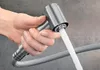 A hand holding a kitchen faucet spray head with water spraying out. Produktbild-Vorschau