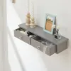 A gray floating shelf with two open drawers mounted on a white wall. The drawers contain various small items, including jewelry and decorative objects. Two tall, twisted candles in wooden candleholders and a framed picture are placed on top of the shelf. Podgląd zdjęcia produktu