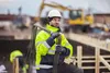 Construction worker on a site carrying rebar. Produktbild-Vorschau