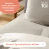 A close-up view of a bed with taupe bedding and a white pillow, with marketing text overlays. Voir les images du produit