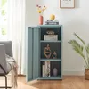 A gray-blue metal cabinet with its door open, displaying decorative items and books on its shelves. The cabinet is placed in a room with a chair and curtains visible. Podgląd zdjęcia produktu