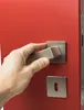 A hand is shown operating a door handle on a red door. Produktbild-Vorschau
