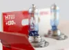 Two car headlight bulbs are displayed in their packaging, with one bulb prominently in the foreground and another slightly out of focus in the background. Anteprima dell’immagine prodotto