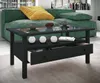A modern living room scene featuring a black coffee table with a glass top, a green sofa with a yellow cushion, and various decorative items. Produktbild-Vorschau