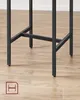 Close-up of the black metal legs of a table against a wooden floor. Náhled obrázku produktu