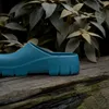 A blue Birkenstock clog sits on a wooden surface with green foliage in the background. Produktbild-Vorschau