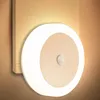 A round LED night light with a motion sensor is mounted on a wall. Podgląd zdjęcia produktu