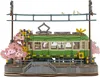 A detailed 3D wooden model of a train station with a green train, cherry blossoms, and overhead wires. Produktbild-Vorschau
