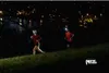 Two people running at night with headlamps on a grassy hill. Náhled obrázku produktu