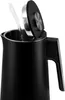 A black electric kettle is being filled with water. Podgląd zdjęcia produktu