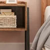 A close-up view of a rustic wooden nightstand next to a bed. Podgląd zdjęcia produktu