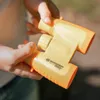 Hands holding yellow and orange binoculars outdoors. Produktbild-Vorschau