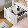 A close-up view of an open drawer in a white nightstand, revealing various items stored inside. Náhľad obrázku produktu