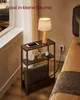 A narrow side table with a lamp, phone, and blanket next to a bed. Produktbild-Vorschau