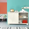 A sideboard with sliding doors and open shelving is displayed in a room with a coral and turquoise wall. The shelves contain decorative items, dishes, and cans. Produktbild-Vorschau
