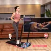 A woman is running on a treadmill in a living room, with an inset image showing someone sleeping in bed. Produktbild-Vorschau