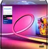 The image shows the packaging for a Philips Hue Play Gradient Lightstrip for a 65-inch TV. The packaging features a gradient of pink and purple colors, with an image of the lightstrip itself creating a colorful glow around a television screen displaying a  Produktbild-Vorschau