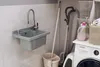 A laundry room or utility area with a sink, washing machine, vacuum cleaner, and cleaning supplies. Anteprima dell’immagine prodotto