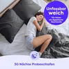 A woman sleeping comfortably in a bed with dark gray bedding. Produktbild-Vorschau