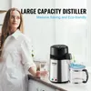 A woman stands next to a water distiller on a countertop. Produktbild-Vorschau