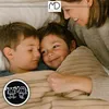 A mother tucks two young boys into bed under a blanket. Anteprima dell’immagine prodotto