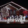A house decorated with Christmas lights and decorations, including a nativity scene, Santa Claus figures, and illuminated trees. Náhled obrázku produktu