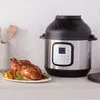 An Instant Pot Duo Crisp multicooker with a roasted chicken on a plate next to it, set on a kitchen counter with a tiled backsplash. Produktbild-Vorschau