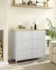 A white dresser with six drawers is placed in a room next to a fireplace and a plant. Náhled obrázku produktu