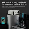 A projector is displayed on a stand, surrounded by other electronic devices like a smartphone, a game console, and a laptop, suggesting connectivity and entertainment options. Náhled obrázku produktu