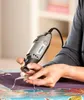 A person is using a Dremel tool to engrave or shape a piece of jewelry. Produktbild-Vorschau