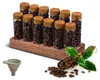 A set of 12 glass storage tubes for coffee beans, displayed on a wooden stand, with a scoop of coffee beans and a funnel in the foreground. Produktbild-Vorschau