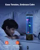 A young boy is lying in bed, looking at a jellyfish lava lamp on a nightstand. The lamp is lit and displays colorful jellyfish. There are icons and text at the bottom of the image highlighting features. Voir les images du produit