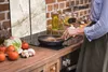A person cooking in a kitchen with vegetables on the counter. Anteprima dell’immagine prodotto