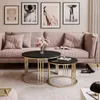 A living room scene with a pink sofa, coffee tables, and artwork.