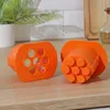 Two orange plastic sausage molds are placed on a wooden surface, with a blurred background of a plant and white tiles. Anteprima dell’immagine prodotto