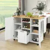 A kitchen cart with a wooden countertop and white cabinets, filled with wine bottles, glasses, and other kitchen items. It is placed in a dining area with a window in the background. Voir les images du produit