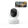 A white Reolink indoor security camera is shown in the foreground, with a smartphone displaying a live feed of a girl and a dog in the background. Anteprima dell’immagine prodotto