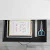 An open drawer containing a framed picture, a ruler, and a pair of scissors. Anteprima dell’immagine prodotto