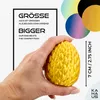 A hand holds a golden, textured egg-shaped object, with text overlays and colorful circles in the background. Produktbild-Vorschau