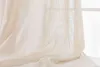 A close-up view of a beige linen-look curtain draped over a surface, with a window visible in the background. Produktbild-Vorschau