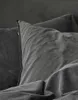 A close-up view of dark gray bedding, focusing on the texture and folds of the fabric. Produktbild-Vorschau