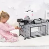 A young girl is playing with a doll's crib with an integrated high chair and changing table. Produktbild-Vorschau