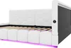 A close-up, angled view of a white upholstered bed frame with a hexagonal pattern on the headboard and LED lighting underneath. Produktbild-Vorschau